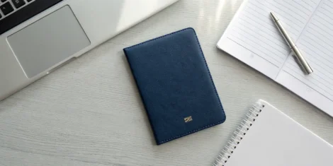 A U.S. passport on a desk with a laptop and documents for learning how to renew your passport.