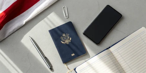 A US passport on a desk next to a notebook and pen for the application.