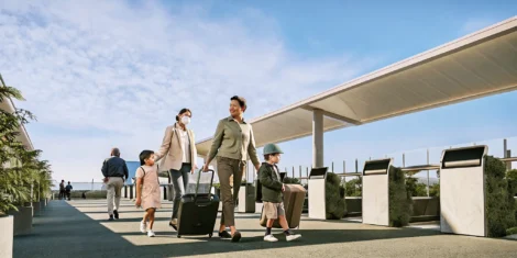 Travelers with carry-on bags moving through a bright airport terminal before an international flight