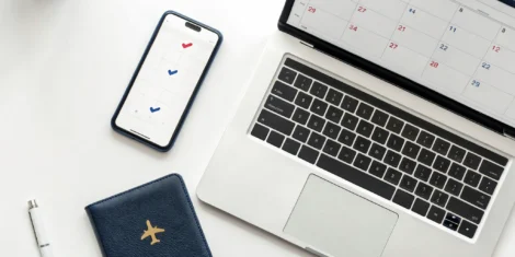 Scheduling a USA visa appointment online with a laptop, passport, and smartphone.